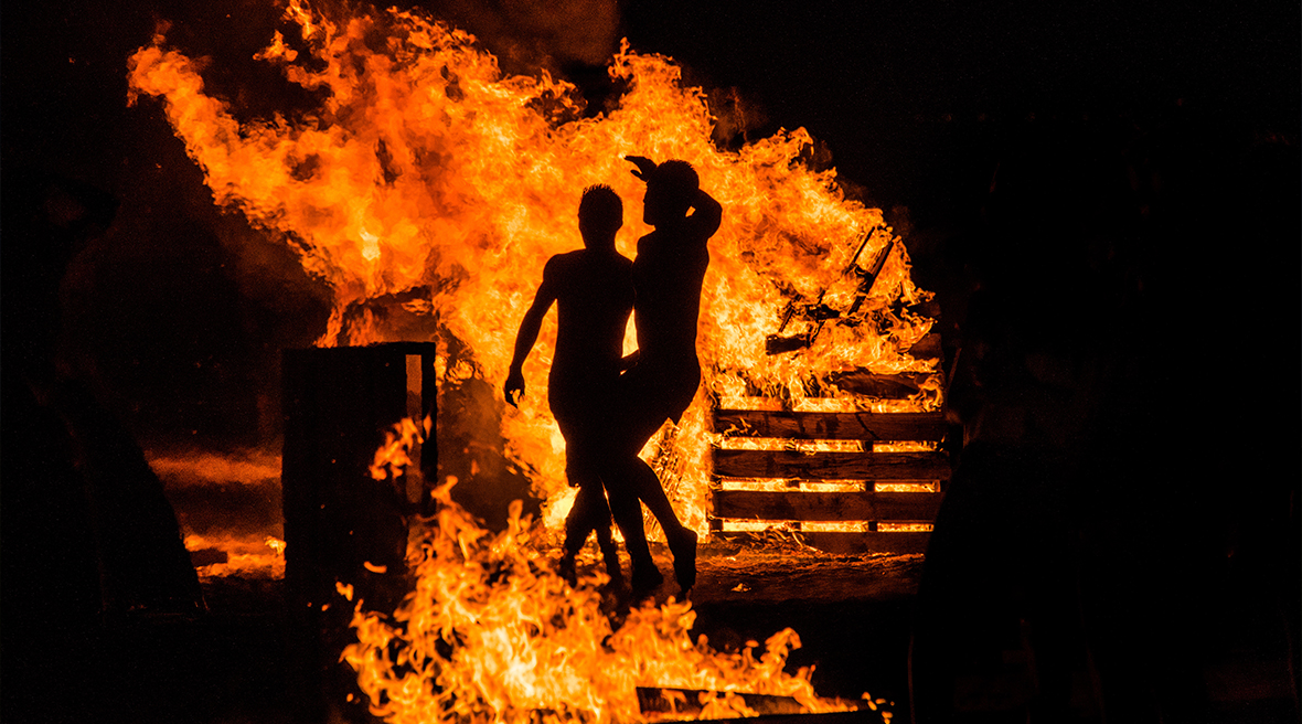 Two people jumping in the bonfires of the night of San Juan in Spain